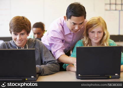 High School Students With Teacher In Class Using Laptops