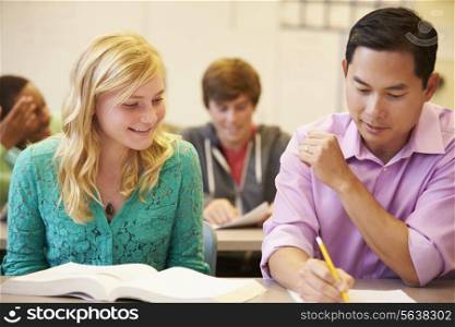 High School Teacher Helping Student With Written Work