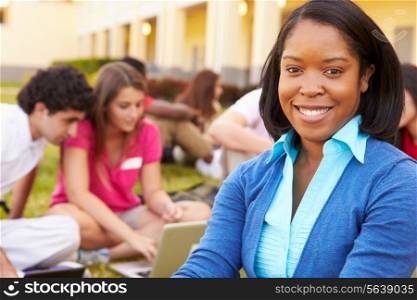 High School Teacher Sitting Outdoors With Students On Campus