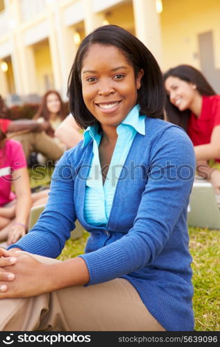 High School Teacher Sitting Outdoors With Students On Campus