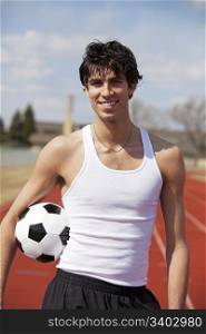 High school teenager with soccer ball under his arm.