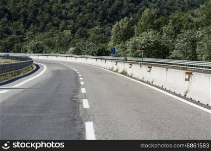 High-speed asphalt road between forests and fields in Tuscany