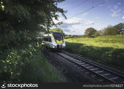 High-speed german train traveling through green nature landscape on sunny day. Train going through countryside scenery near Schwabisch Hall, Germany