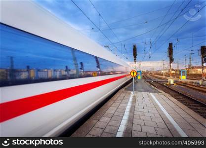 High speed passenger train on tracks in motion at sunset. Commuter train. Railway station in Nuremberg, Germany. Railroad with vintage toning