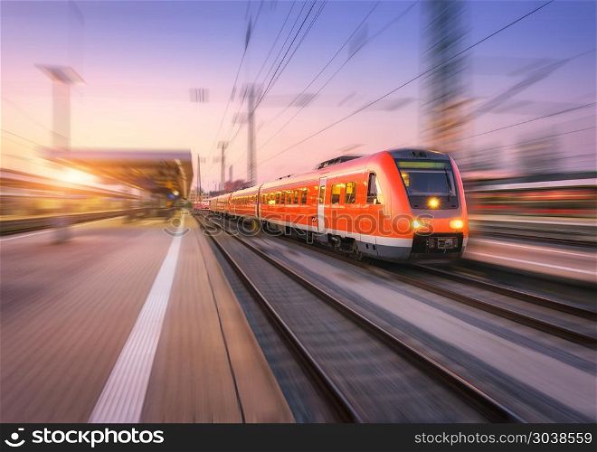 High speed red train with motion blur effect on the railway stat. High speed red train with motion blur effect on the railway station at sunset. Landscape. Modern intercity passenger train in motion on the railway platform at dusk. Commuter vehicle on railroad