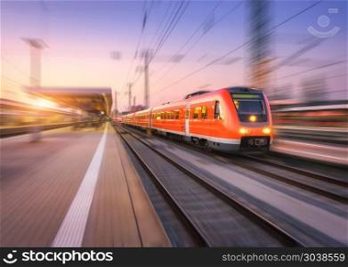 High speed red train with motion blur effect on the railway stat. High speed red train with motion blur effect on the railway station at sunset. Landscape. Modern intercity passenger train in motion on the railway platform at dusk. Commuter vehicle on railroad