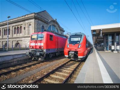High speed train and old train on the railway station at sunset. Nuremberg, Germany. Modern intercity train on the railway platform. Industrial. Commuter trains on railroad. Passenger transportation. High speed train and old train on the railway station