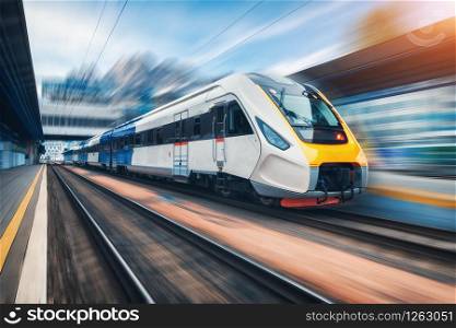 High speed train in motion on the railway station at sunset. Modern intercity passenger train with motion blur effect on the railway platform. Industrial. Railroad in Europe. Nommercial transportation