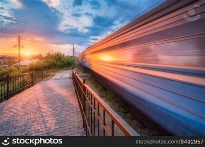 High speed train in motion on the railway station at sunset in summer. Moving modern intercity passenger train, railway platform, green trees and sunlight. Railroad in Urkaine. Railway transportation