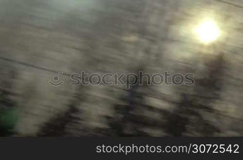 High speed traveling by train in the evening. View of passing landscape with woods and sun in the sky