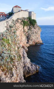 High steep cliffs at the Adriatic Sea with fortification of the Old City of Dubrovnik atop in Croatia, Dalmatia region.