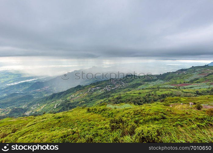 High view beautiful nature landscape of the mountain forest cloud and the rain is falling on the road through the rural village, way up to the Phu Thap Berk viewpoint, Phetchabun, Thailand. Phu Thap Berk when it rains