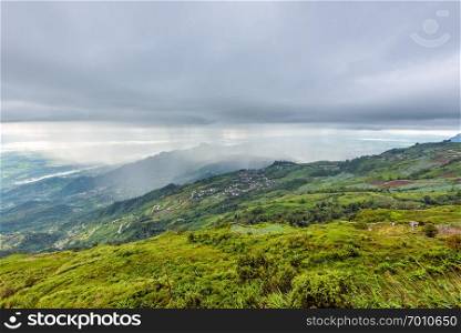 High view beautiful nature landscape of the mountain forest cloud and the rain is falling on the road through the rural village, way up to the Phu Thap Berk viewpoint, Phetchabun, Thailand. Phu Thap Berk when it rains