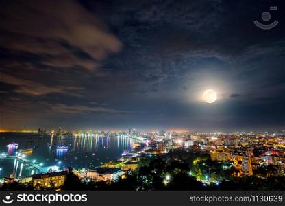 High view on viewpoint full moon above cityscape with colorful light at the sea beach of ??Pattaya Bay, beautiful landscape Pattaya City at night scene landmark in Chonburi, Travel Asia to Thailand. Full moon above Pattaya City at night, Thailand