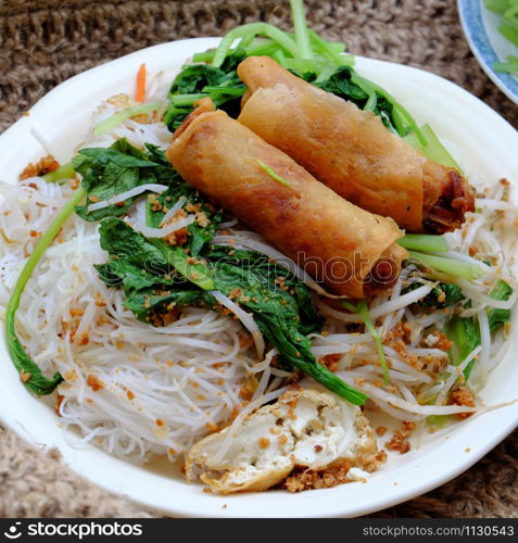 High view Vietnamese vegetarian food for breakfast, close up plate of rice noodle with fried spring roll and vegetables for vegan meal, simple but delicious and healthy food