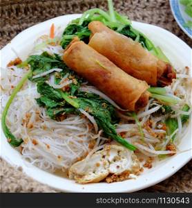 High view Vietnamese vegetarian food for breakfast, close up plate of rice noodle with fried spring roll and vegetables for vegan meal, simple but delicious and healthy food