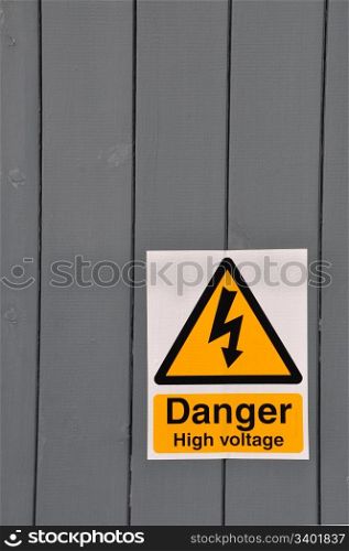 high voltage danger yellow sign on a wooden plank background