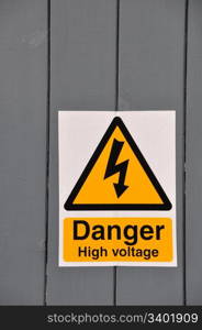 high voltage danger yellow sign on a wooden plank background