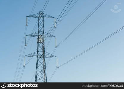 high voltage electric power lines against a blue sky - with copyspace