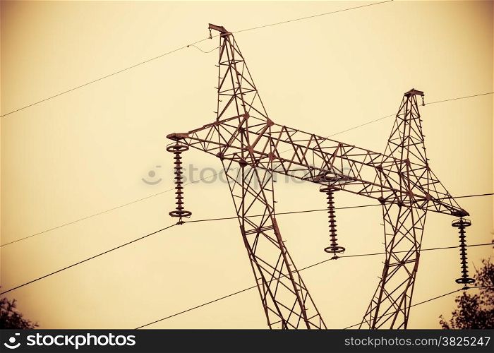 High voltage electric power transmission towers pylons in sunset sky background