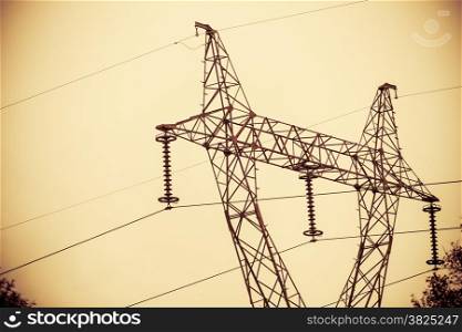 High voltage electric power transmission towers pylons in sunset sky background