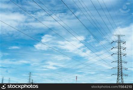 High voltage electric pylon and electrical wire against blue sky and white clouds. Bottom view of Electricity pylon with sunlight. High voltage grid tower with wire cable. Power and energy concept.