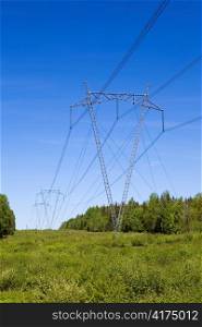 High-voltage line of electricity transmissions on field , among wood