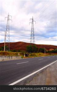 High-voltage Power Line Crosses The Paved Road In Tuscany