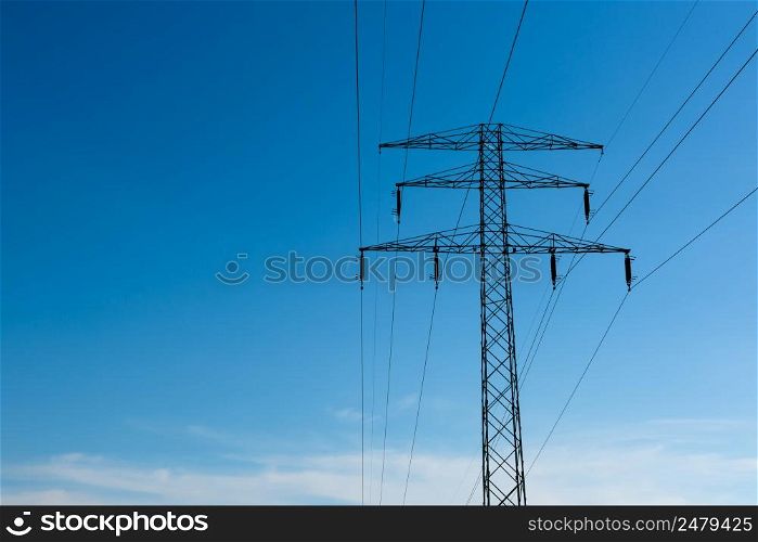 High voltage power lines on pylon at sunny day with blue sky as copy space