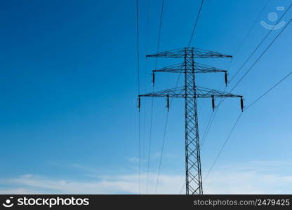 High voltage power lines on pylon at sunny day with blue sky as copy space