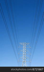 High voltage power pole against blue sky