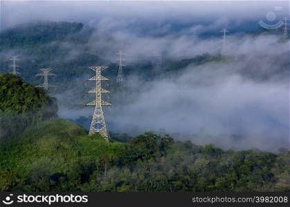 High voltage power transmission towers in fog on mountain mae moh lampang.. Electric transmission towers in fog
