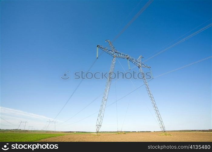 High voltage pylons on the background of blue cloudless sky