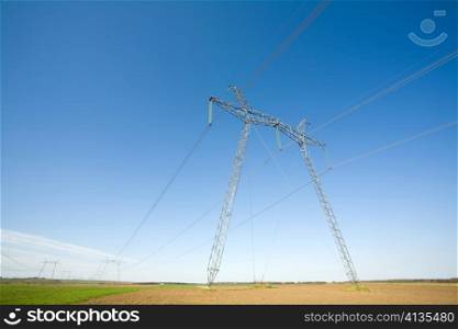 High voltage pylons on the background of blue cloudless sky
