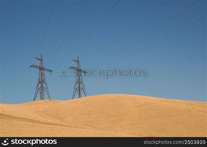 high voltage tower in a sandy area against the blue sky. post electric, insulated