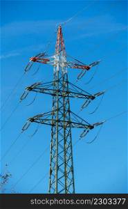 High voltage tower with electricity transmission power lines against blue sky