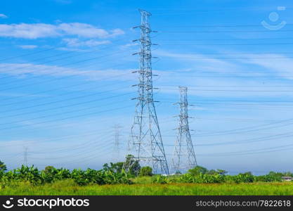 High voltage towers. The meadow below. Industry and nature coexist in appropriate Slightly cloudy sky.