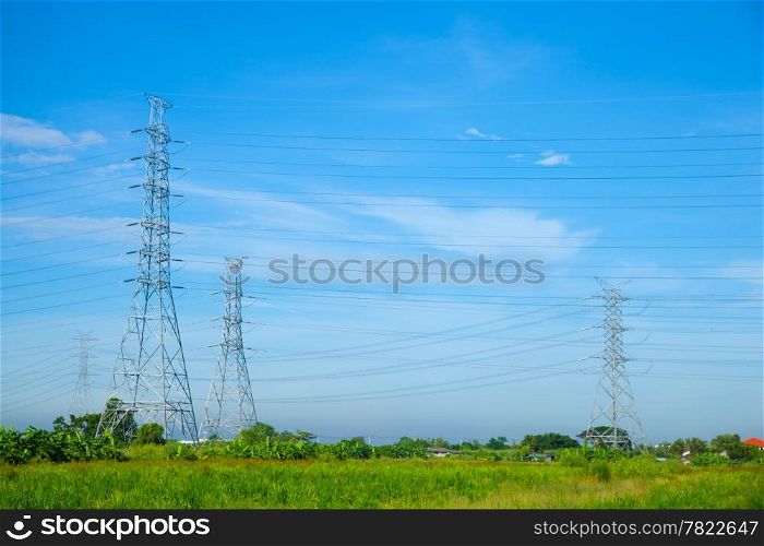 High voltage towers. The meadow below. Industry and nature coexist in appropriate Slightly cloudy sky.