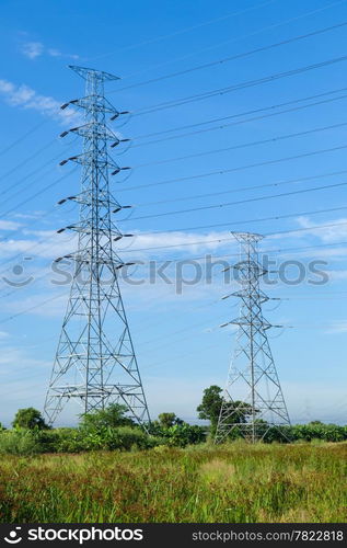 High voltage towers. The meadow below. Industry and nature coexist in appropriate Slightly cloudy sky.