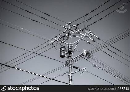 High voltage wires multi direction on electric pole with transformer against bright blue sky