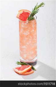 Highball glass of cocktail with red grapefruit and gin with vodka with ice cubes, fruit slice and rosemary on white background.