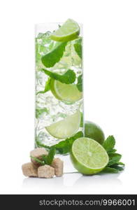 Highball glass of Mojito summer alcoholic cocktail with ice cubes mint and lime on white background with cane sugar and raw lime