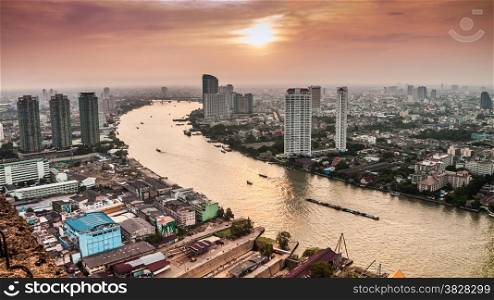 Hight view of Bangkok city with modern building and inland water transportation along Chaopraya river on evening