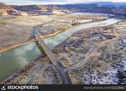 highway across Colorado River with the remains of historic Dewey Bridge above Moab In Utah, aerial view of winter scenery, travel concept
