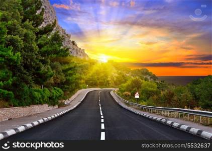 Highway against mountains and a dramatic sunset