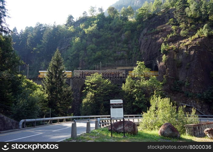 Highway and cargo train on the railway bridge near mountain in Switzerland
