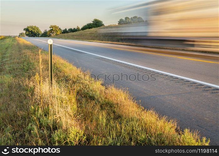 highway in Nebraska Sandhills with a blurred truck, late summer or early fall scenery in morning light