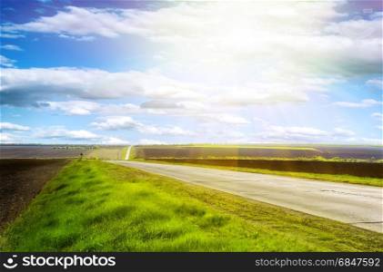 Highway in the hills on a clear sunny day with blue sky and green grass on the roadside. Highway on a clear sunny day