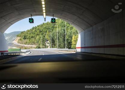 Highway tunnel. Signs in tunnel. Mountain road. Travel and traffic concept. View from inside the car.
