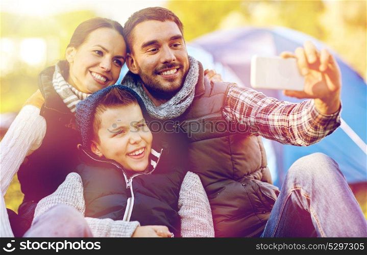 hike, technology and travel concept - happy family with smartphone taking selfie at campsite. family with smartphone taking selfie at campsite